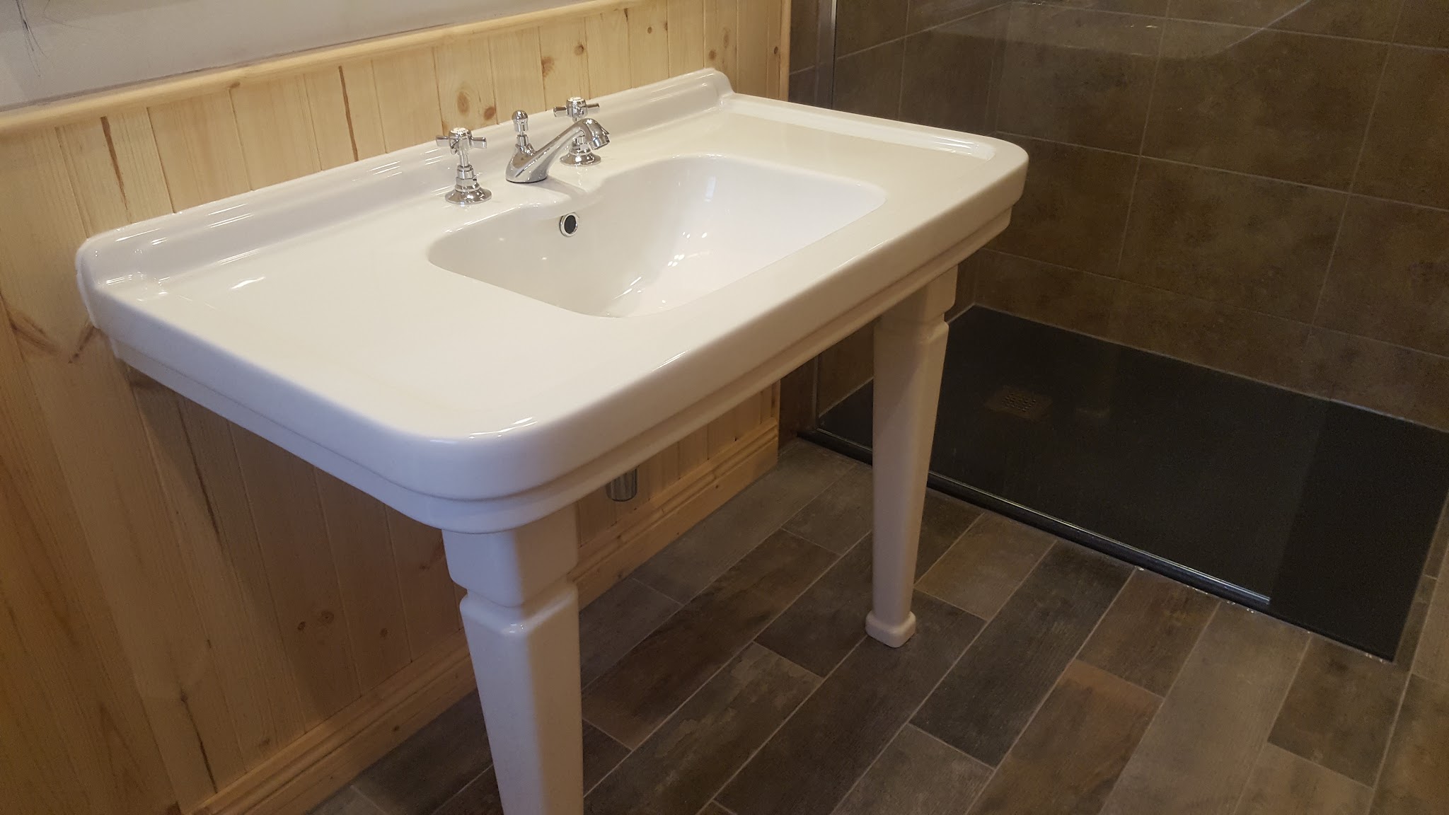 Pedestal basin with chrome taps in a panelled bathroom