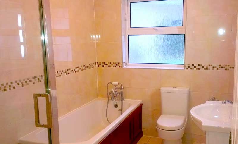 Bathroom with a bath, toilet and basin and a mosaic tile border