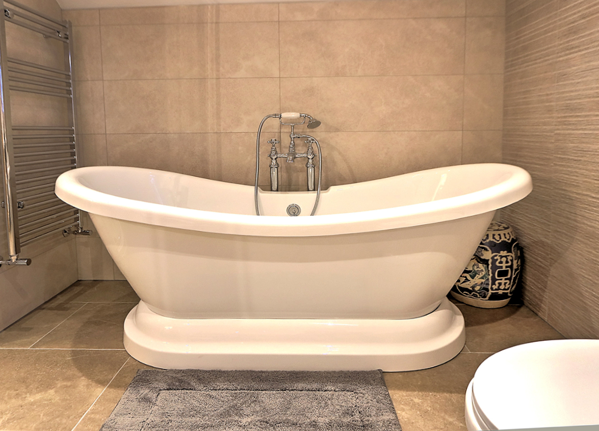 Freestanding slipper bath with a floor-standing mixer and a heated towel rail