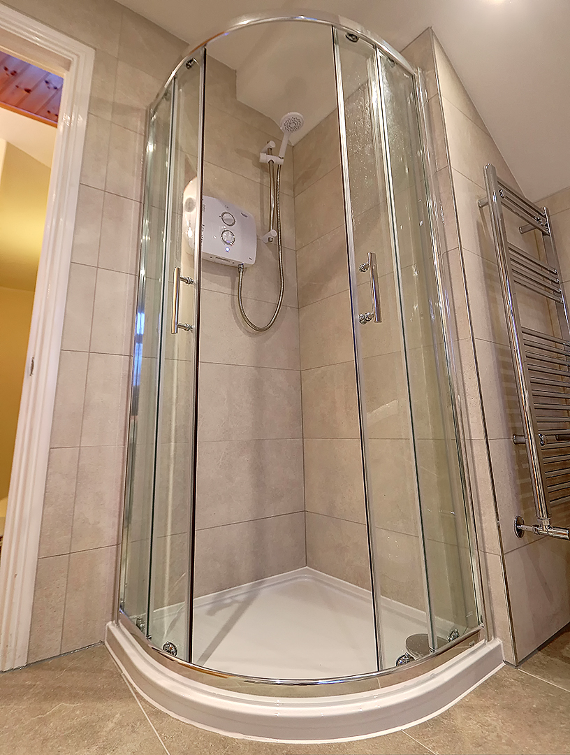 Quadrant shower enclosure with a heated towel rail alongside