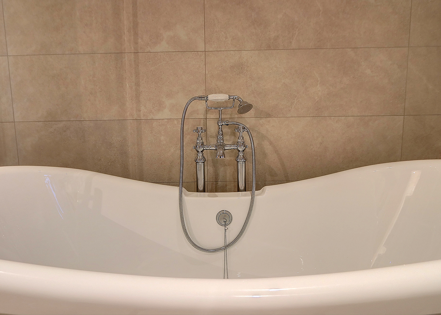 Chrome bath mixer with a hand shower on a slipper bath